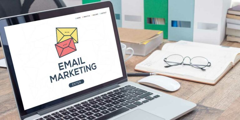 COMPUTER PORTATILE APERTO SU UNA SCRIVANIA CON LA SCRITTA SULLO SCHERMO "E-MAIL MARKETING".